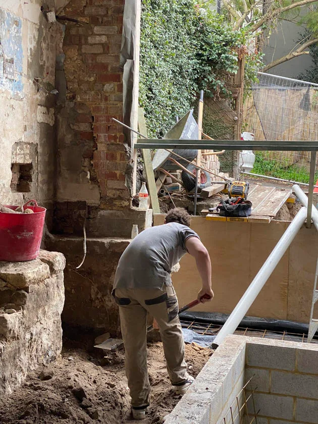 Excavating beside a brick footing for a plumbing repair